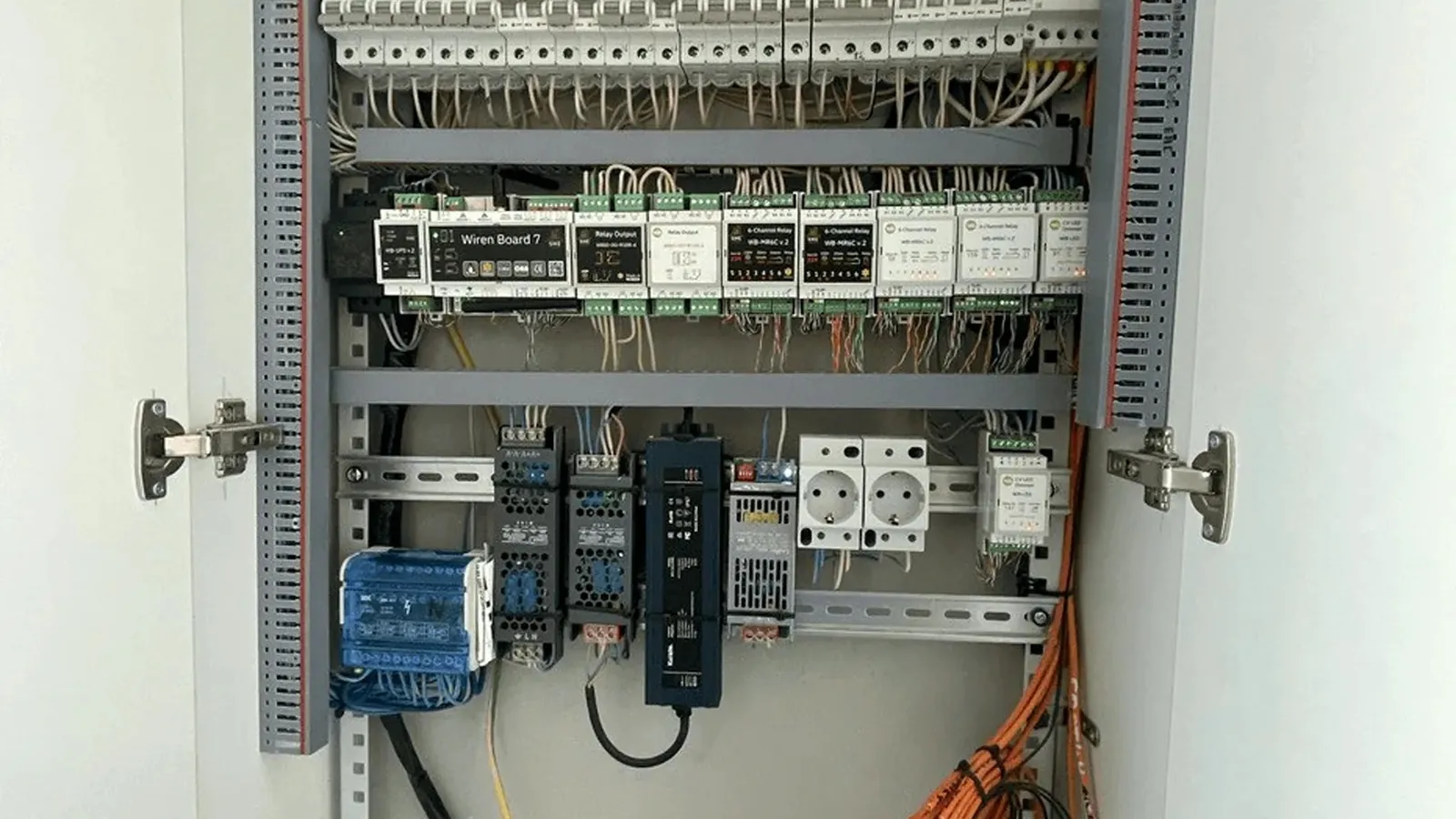 открытый щит автоматизации с контроллером Wiren Board 7 и рядом модулей реле